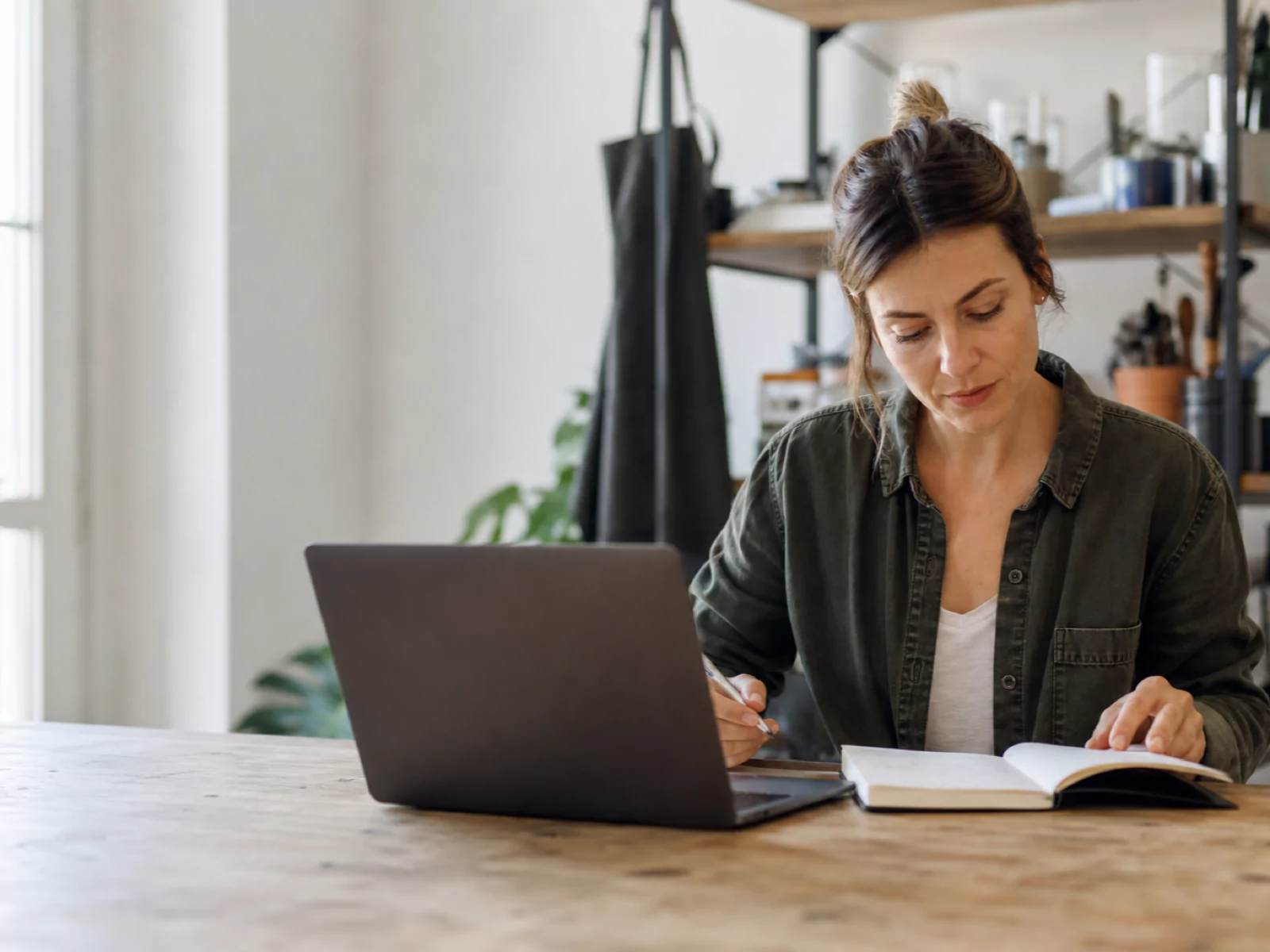 Small-business owner planning work beside her laptop in a bright workspace.